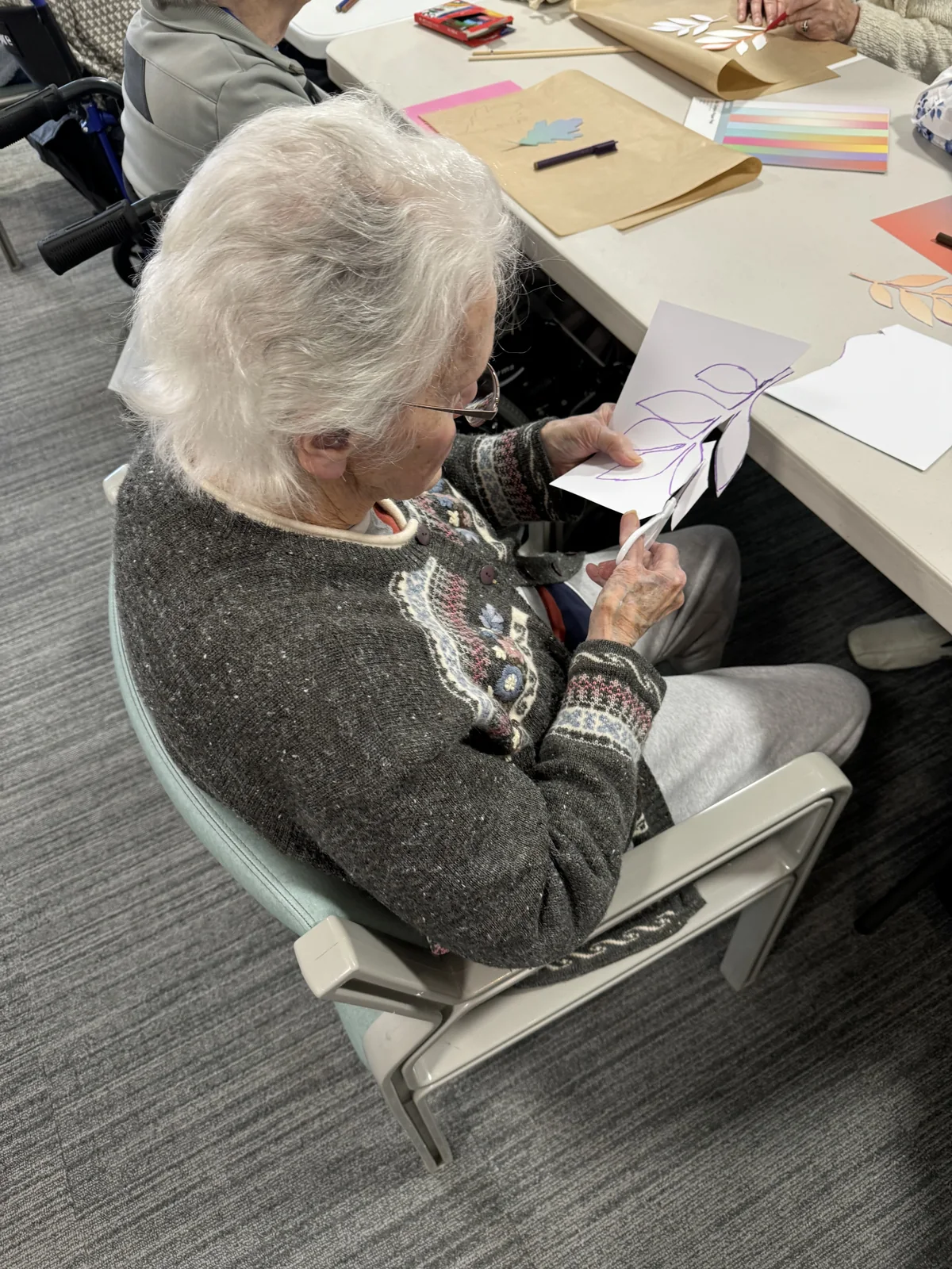 A resident cutting along the drawn outline of a paper flower