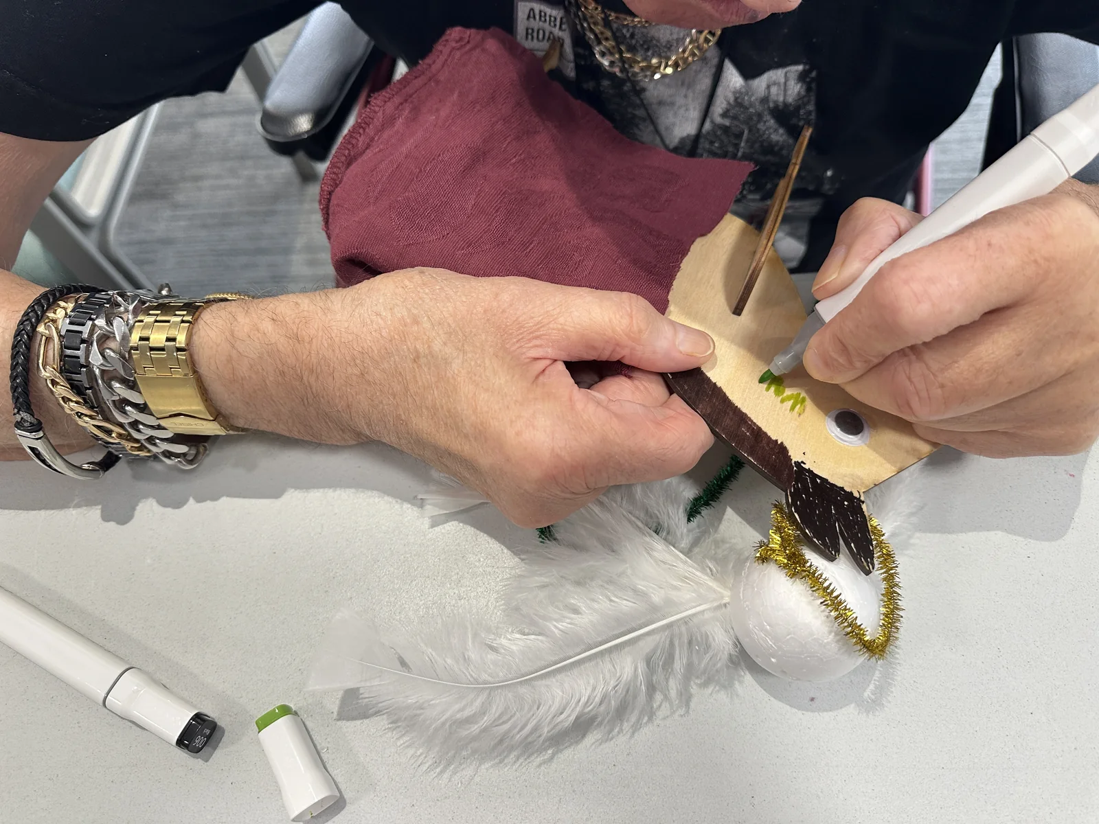A resident drawing green details on a wooden animal with a marker