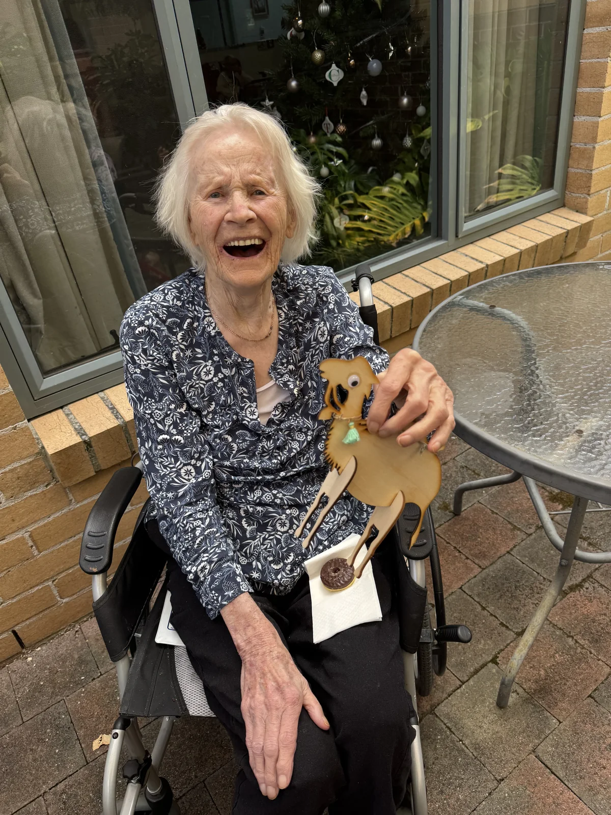 A resident holding a decorated wooden camel outdoors