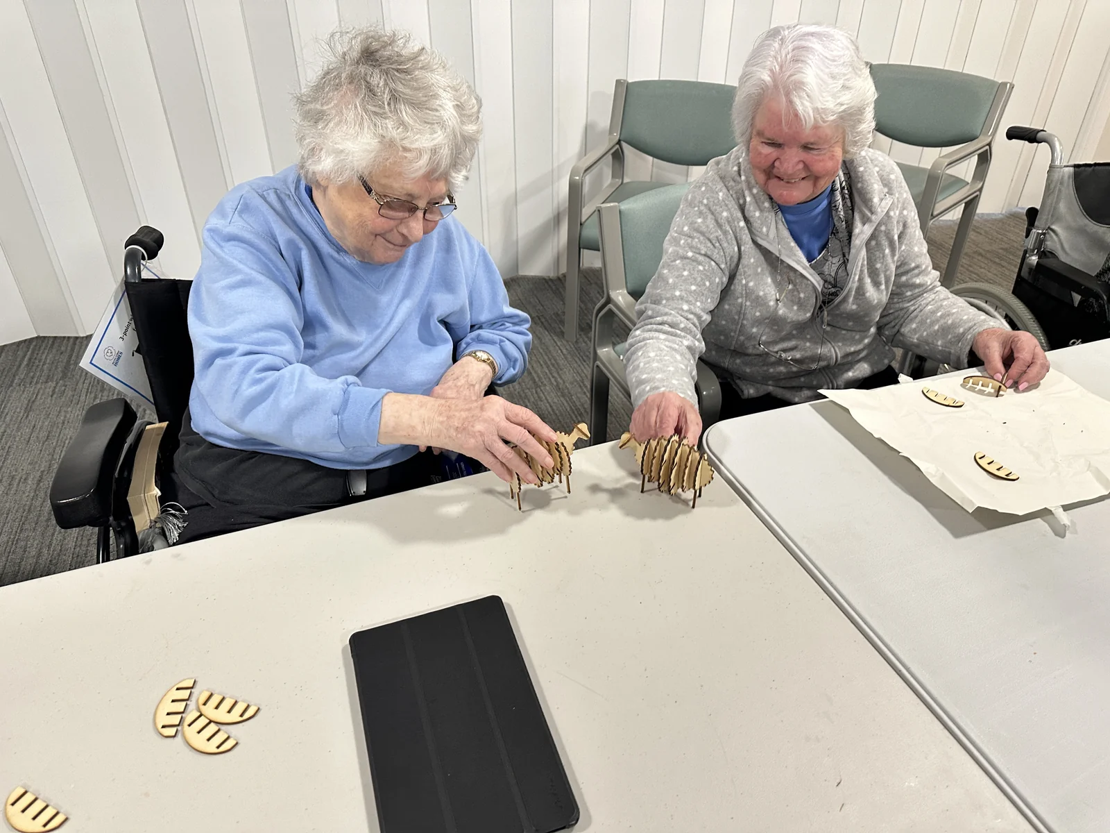Participants assembling wooden sheep models at a table