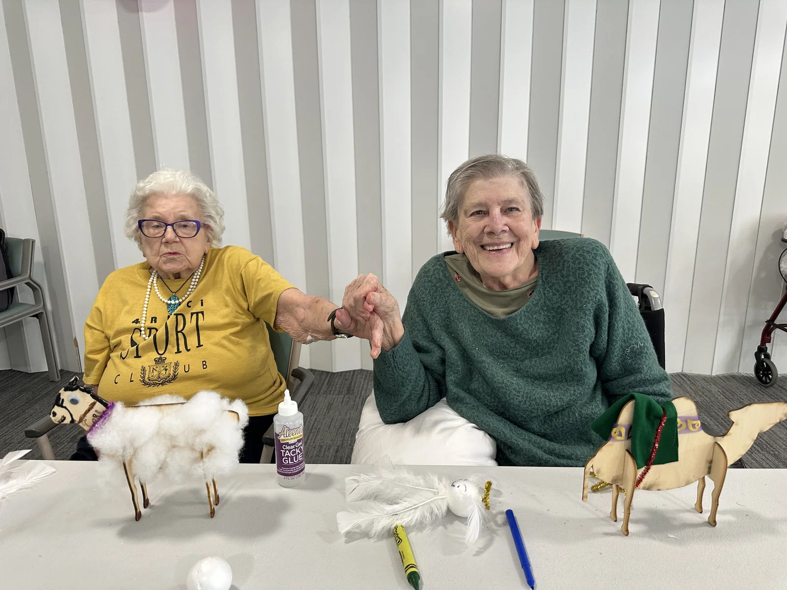 Two residents seated with their differently decorated wooden animals