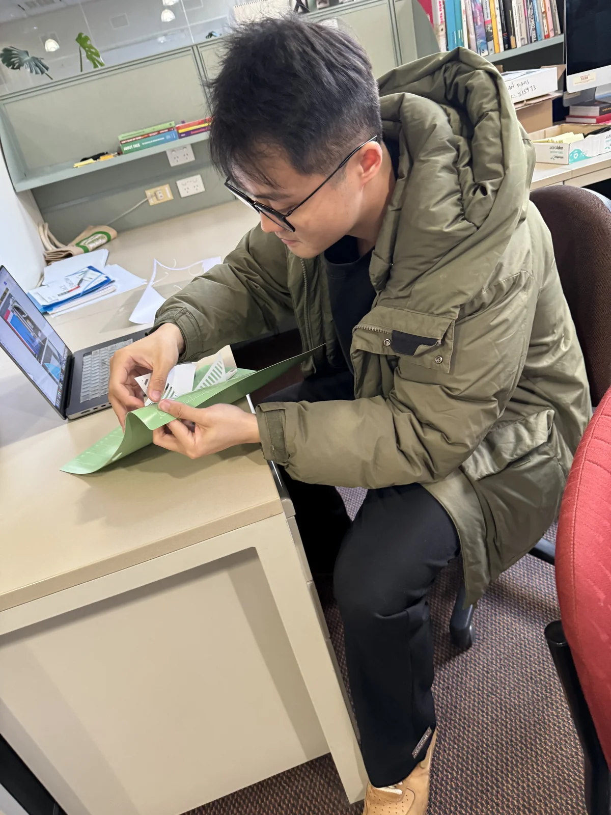 Xingting Wu carefully removing cut paper shapes from a green Cricut mat