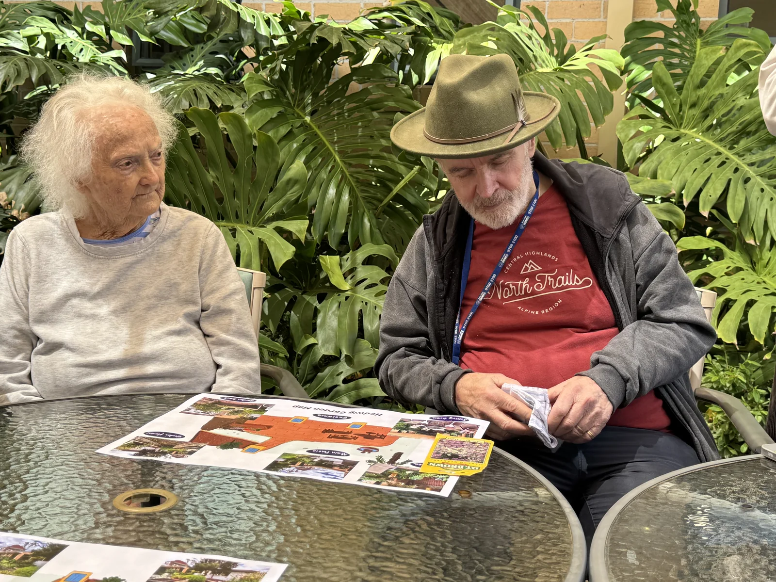 Two residents looking at illustrated nature materials together at a garden table