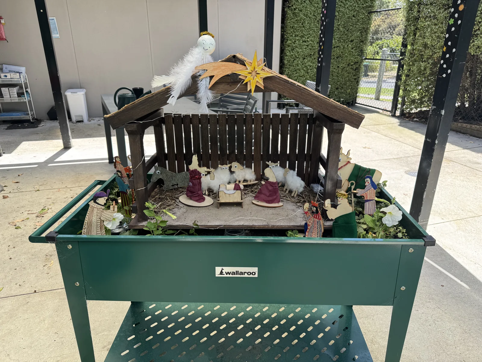 Completed Nativity display with hand-decorated figures in a raised garden bed