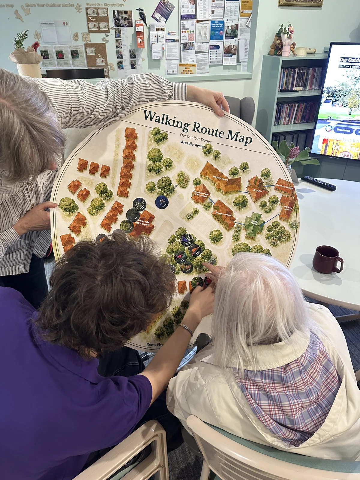 Residents and staff looking closely at the walking route map held upright
